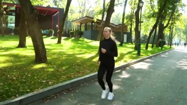 Sonbaharın başında güneşli parkta koşan bir kadın