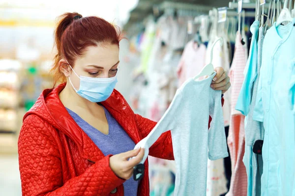 Kadın, salgın sırasında mağazadan bebek kıyafetleri alıyor.