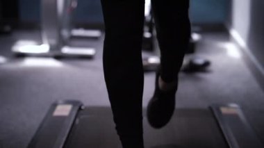 Spor salonunda koşu bandında koşan kadın ayakları.