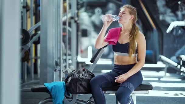 Femme assise dans le gymnase et l'eau potable après l'entraînement — Video