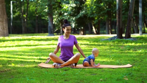 Moeder training in het park en baby zitten naast — Stockvideo