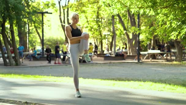 Fit femme étirant les jambes avant de faire du jogging dans le parc — Video