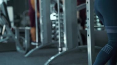 Bir kadın halterle yaklaşıyor ve onunla çömeliyor.