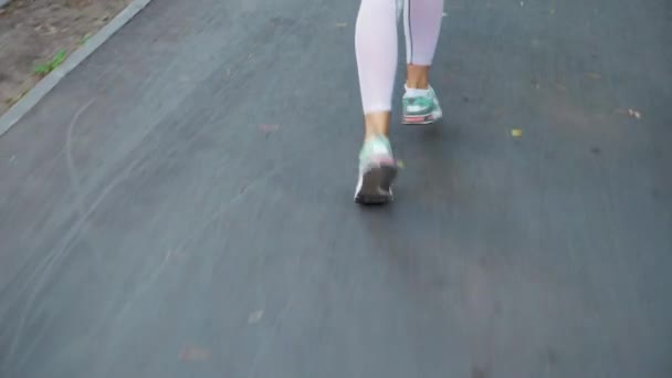 Kvinnliga fötter som löper på asfalterad väg — Stockvideo