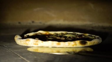 Büyük restoran fırınının içinde kürekle dönen pizzanın yavaş çekimleri.
