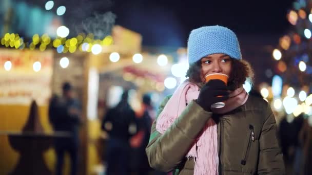 Czarny dziewczyna mając gorący napój na Boże Narodzenie rynek — Wideo stockowe