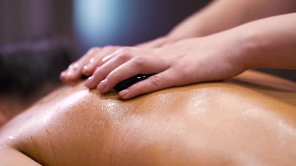 Massage aux pierres sur le dos féminin dans un spa bien-être — Video