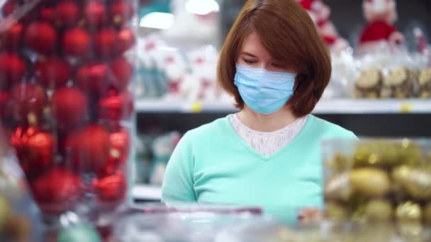 Vrouw kijkt naar kerstversieringen in de winkel tijdens een pandemie — Stockvideo