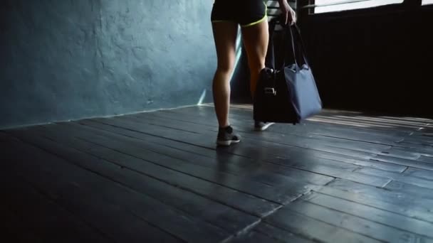 Женщина-спортсмен входит в спортзал и сидит на полу — стоковое видео