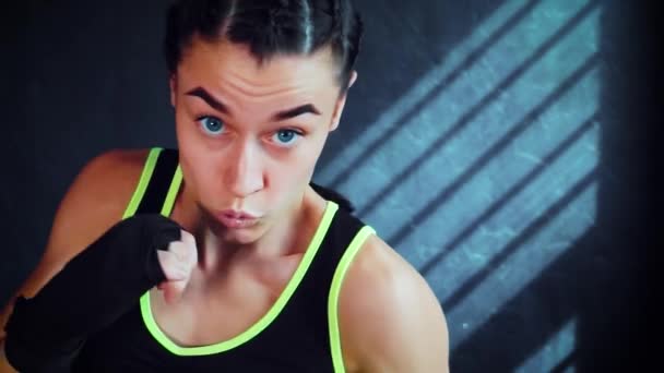 Женщина-боксер смотрит в камеру и практикует удары в спортзале — стоковое видео