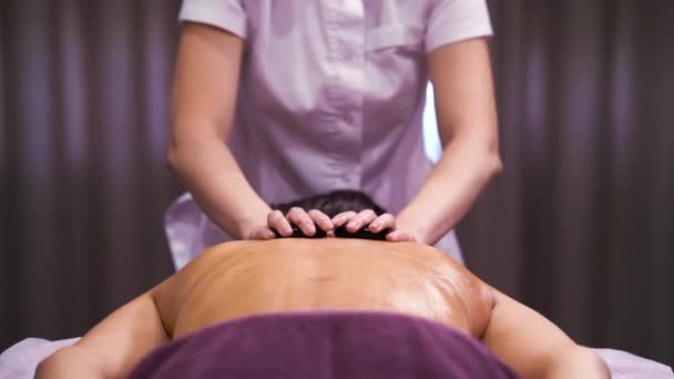 Mujer recibiendo masaje de piedra en la espalda en spa de bienestar — Vídeo de stock