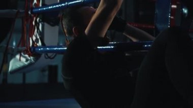 Boksör boks ringinde abdominal egzersizler yapıyor.