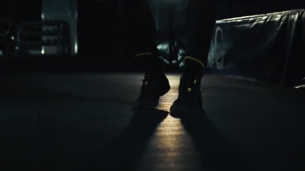 Чоловічі ноги в кросівках стрибають на мотузці в темному тренажерному залі — стокове відео