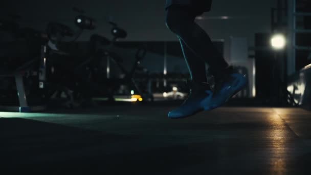 Ноги спортсмена, прыгающего по веревке в темном зале — стоковое видео