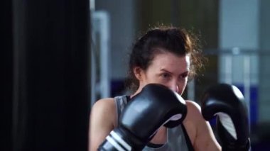 Kadın boksör spor salonunda yumruk pratiği yapıyor.
