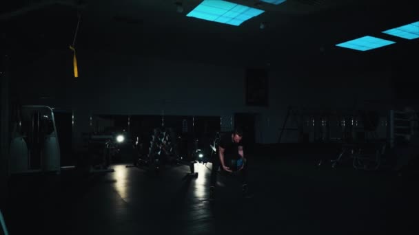 Hombre fuerte lanzando bola pesada en el gimnasio oscuro — Vídeos de Stock