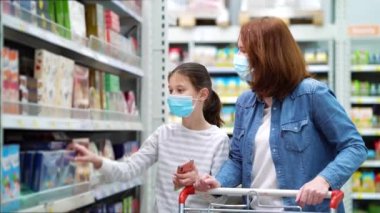 Anne ve kız süpermarkette şeker reyonunda maskeli.