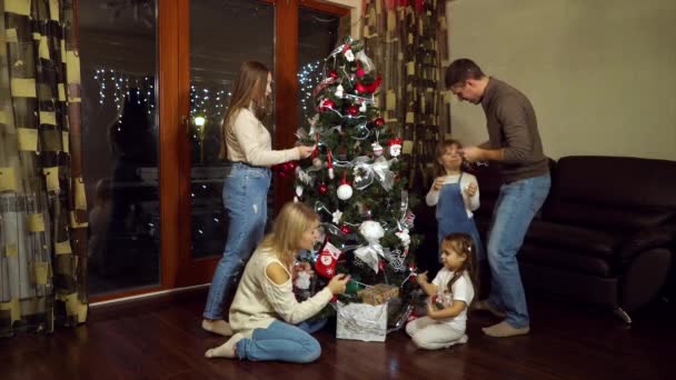 Familia decorando árbol de Navidad juntos — Vídeo de stock