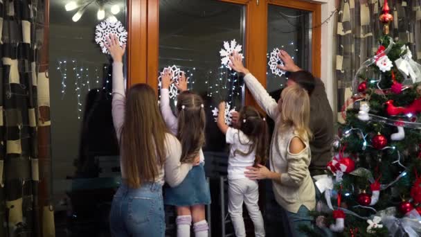 窓に紙の雪片を取り付ける家族 — ストック動画