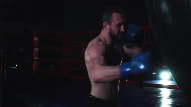 Boxer berlatih dengan karung tinju di dekat ring tinju — Stok Video
