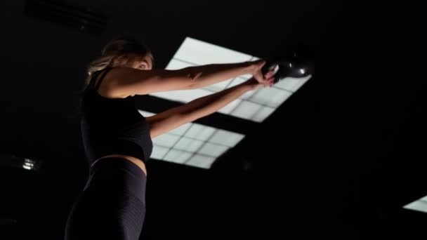 Fit woman training with kettlebell in dark gym — Stockvideo