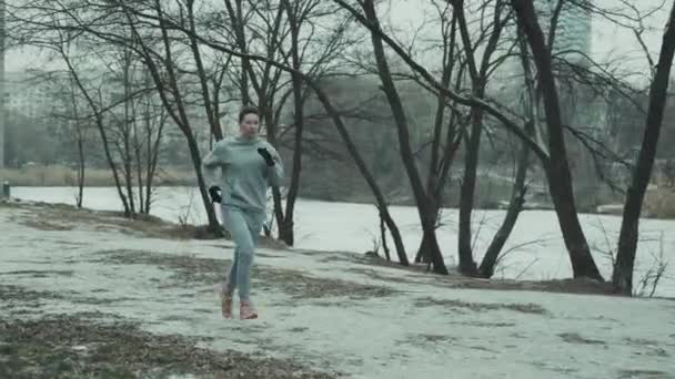 겨울에 도시 공원에서 조깅하는 운동 선수 여자 — 비디오