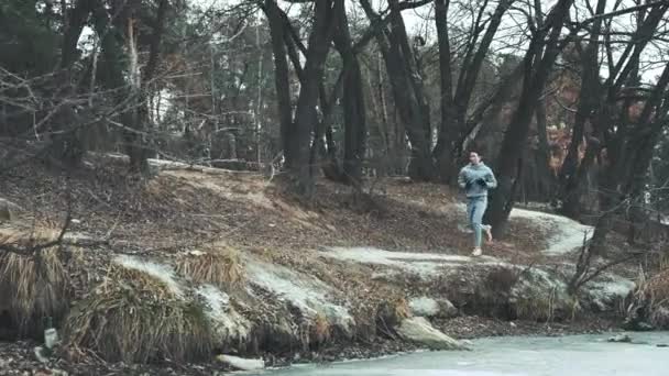 Mujer en forma trotando entre los árboles en el bosque de invierno — Vídeos de Stock