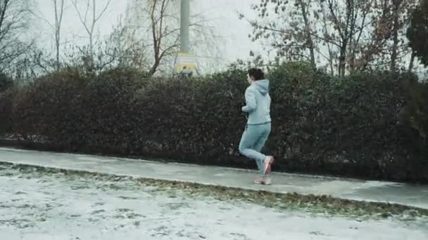 Fitte Frau joggt auf schneebedecktem Gehweg — Stockvideo