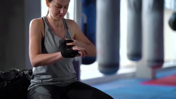 Boxer feminino envolvendo pulsos com ligaduras antes do treinamento em ginásio — Vídeo de Stock