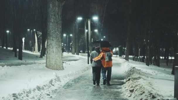 Pareja de mediana edad caminando por la noche en un clima desagradable — Vídeos de Stock