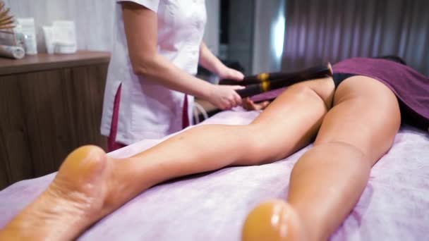 Frau lässt sich in Wellness-Spa mit Bambusstäben massieren — Stockvideo