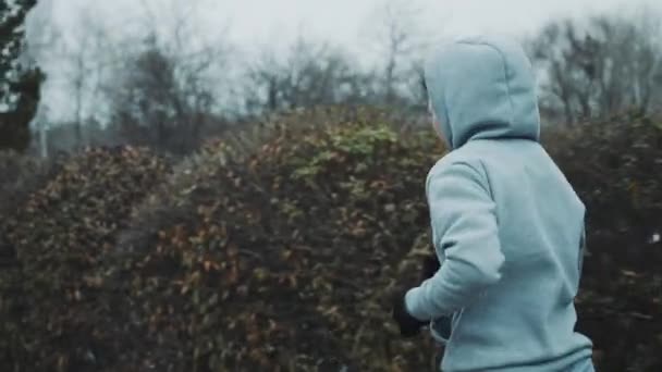Kvinnlig joggare i hoodie träning i vinterpark — Stockvideo