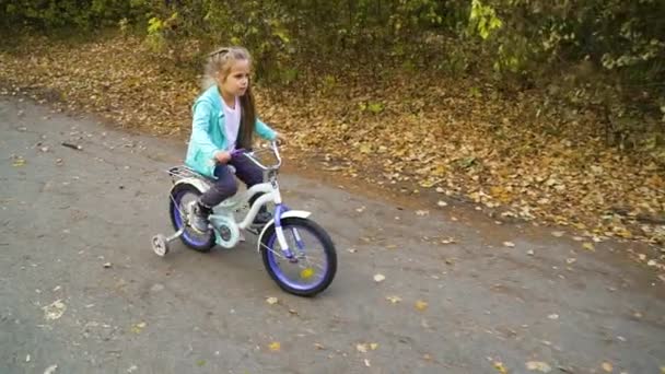 Malá holka na kole na čtyřech kolech kolo v parku — Stock video