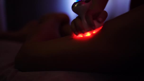 Tratamiento contra la celulitis con luz roja en la pierna femenina en el spa de bienestar — Vídeo de stock