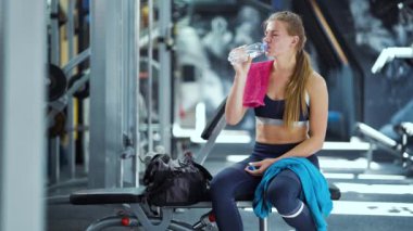 Spor salonunda idmandan sonra su içen sağlıklı bir kadın.