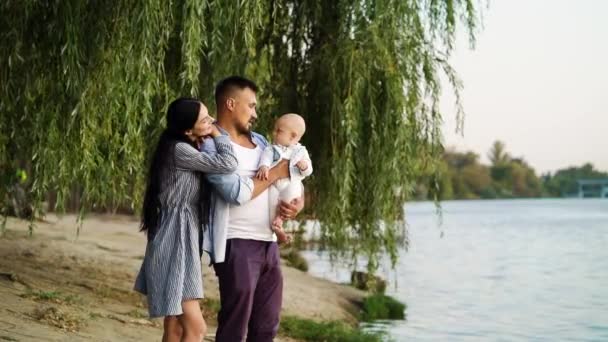 Nehir kıyısında bebeği olan sevgi dolu bir aile — Stok video