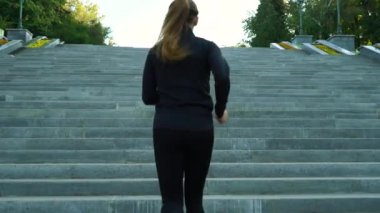 Şehirde merdivenlerde koşan zinde bir kadın.