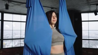 Yoga dersinde hamağa sarılan sağlıklı bir kadın.