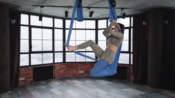 Женщина делает асану в классе йоги мух — стоковое видео