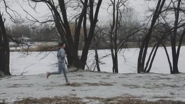 Frau joggt im Winter nahe zugefrorenem See — Stockvideo