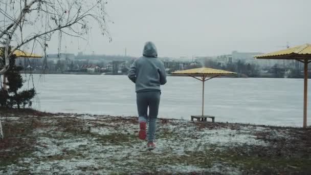 Adatta donna che corre sulla spiaggia innevata e alza le mani nella gioia — Video Stock