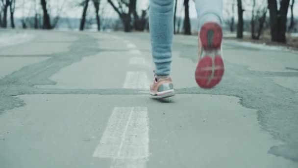 Weibliche Füße joggen im Winter auf Straße — Stockvideo