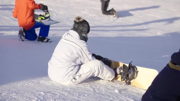Női snowboard rögzítő csizma a fedélzeten havas lejtőn — Stock videók