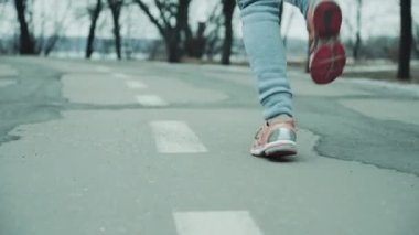 Kadın ayakları ağır çekimde yolda koşuyor.