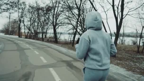 Fitte Frau im Kapuzenpullover joggt im Winter — Stockvideo