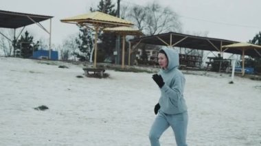 Karla kaplı plajda koşan kadın koşucu.