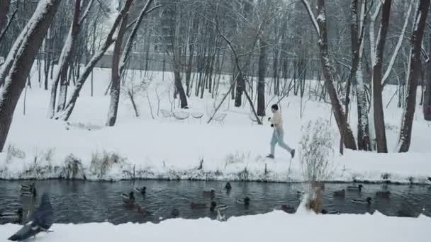 Man joggen langs de rivier in de winter — Stockvideo