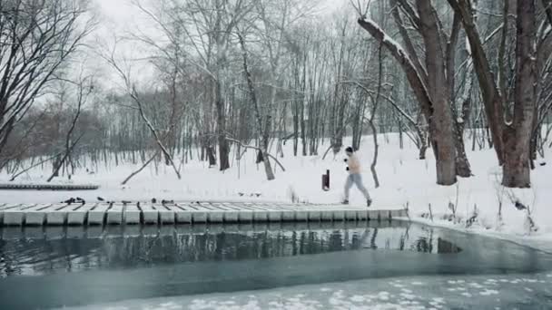 Jogger oversteken rivier op brug in winterpark — Stockvideo