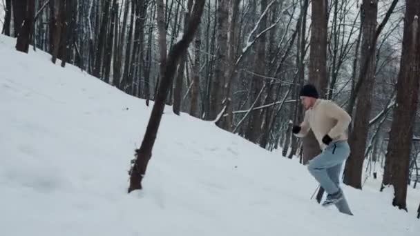Man rent de heuvel op in het winterbos — Stockvideo