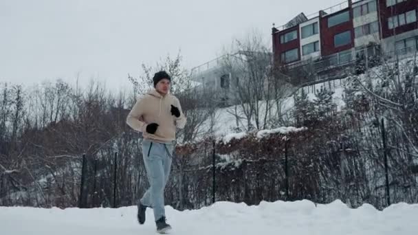 Man joggen in winterpark tegen stadsgebouwen — Stockvideo